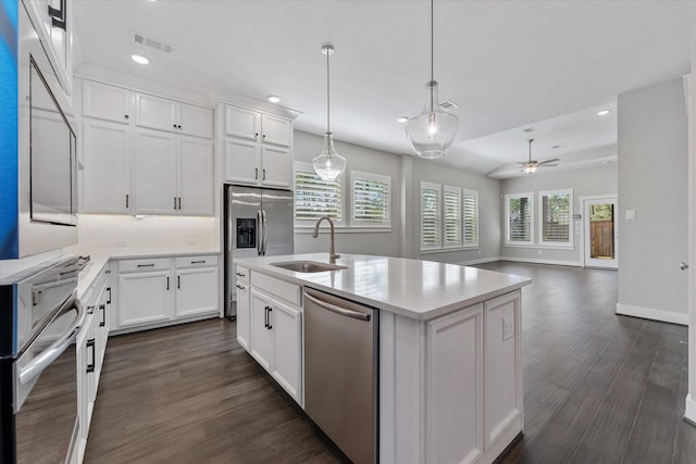 kitchen with visible vents, an island with sink, appliances with stainless steel finishes, open floor plan, and light countertops