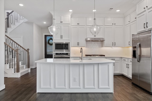 kitchen with under cabinet range hood, a sink, light countertops, appliances with stainless steel finishes, and hanging light fixtures