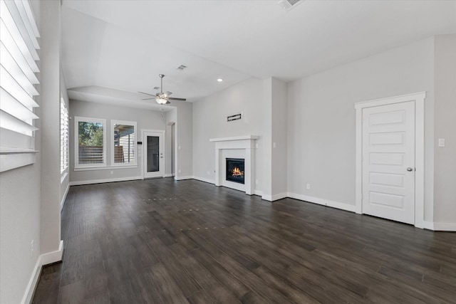 unfurnished living room with dark wood-style floors, a glass covered fireplace, baseboards, and a ceiling fan