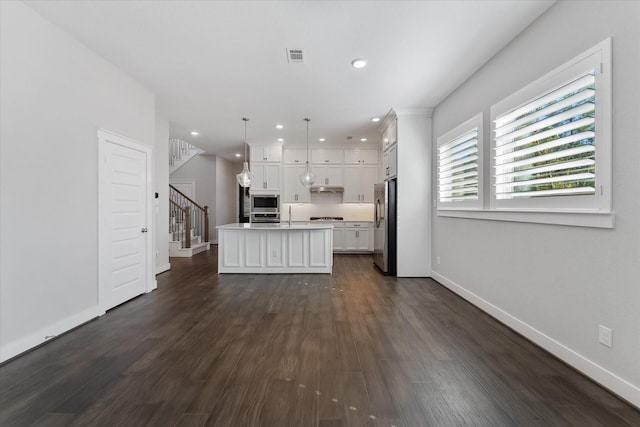 kitchen with pendant lighting, a center island with sink, light countertops, appliances with stainless steel finishes, and white cabinetry