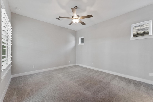 carpeted empty room featuring baseboards, visible vents, and ceiling fan