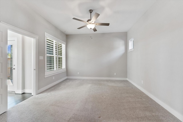 spare room featuring a healthy amount of sunlight, baseboards, and dark carpet