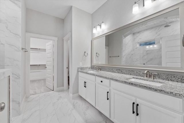 bathroom featuring double vanity, marble finish floor, a spacious closet, and a sink