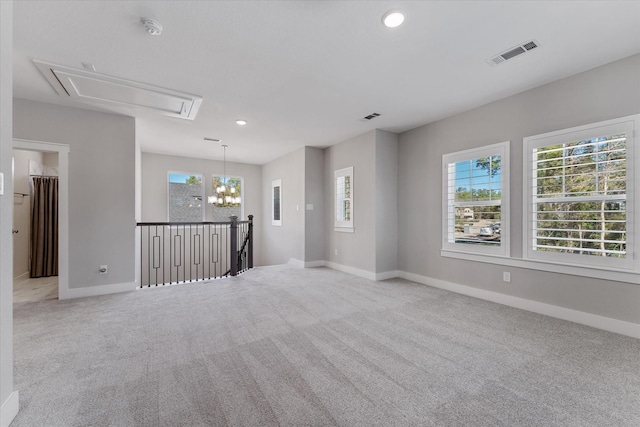 unfurnished room with light carpet, attic access, visible vents, and baseboards