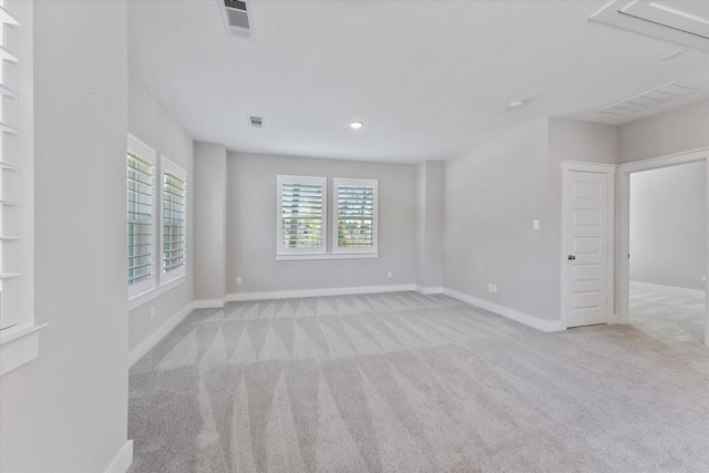 empty room featuring baseboards, visible vents, and light colored carpet