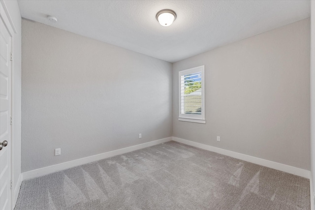 carpeted empty room with a textured ceiling and baseboards