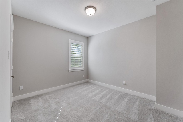 spare room with light colored carpet and baseboards