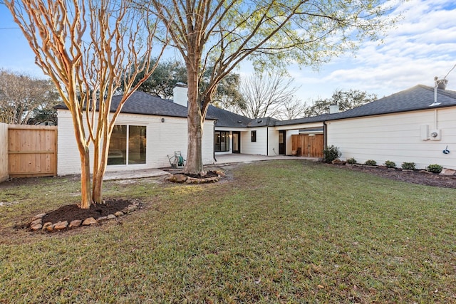 rear view of property with brick siding, a patio, a lawn, and fence