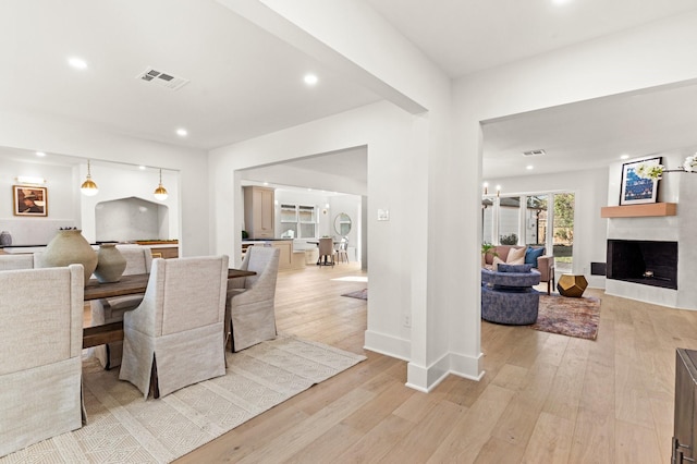 dining space with a fireplace, recessed lighting, visible vents, light wood-type flooring, and baseboards