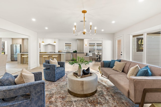 living room featuring visible vents, baseboards, light wood-style flooring, an inviting chandelier, and recessed lighting