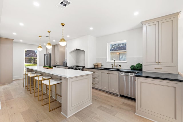 kitchen with a sink, visible vents, appliances with stainless steel finishes, a center island, and pendant lighting