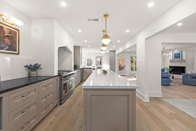 kitchen featuring range with two ovens, gray cabinetry, a peninsula, open floor plan, and decorative light fixtures