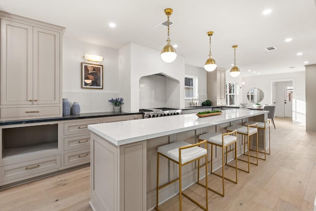 kitchen featuring hanging light fixtures, light wood-type flooring, visible vents, and a sink