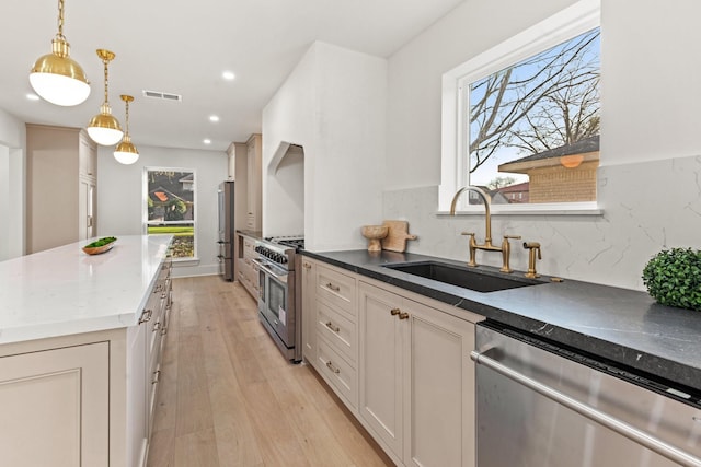 kitchen with visible vents, light wood-style flooring, hanging light fixtures, stainless steel appliances, and a sink