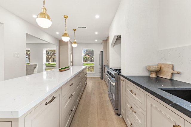 kitchen featuring visible vents, appliances with stainless steel finishes, decorative light fixtures, light stone countertops, and light wood-type flooring