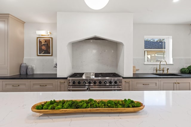 kitchen featuring dark stone counters, tasteful backsplash, a sink, and double oven range