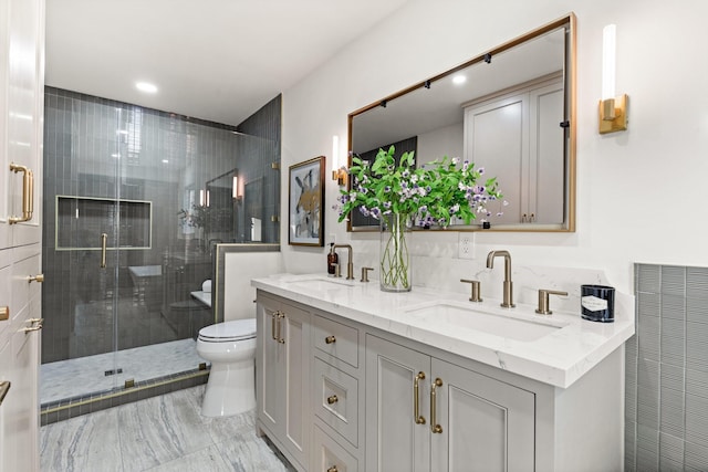 bathroom featuring a stall shower, a sink, toilet, and double vanity