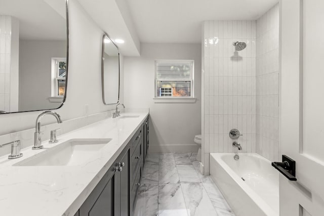 bathroom featuring double vanity, marble finish floor, baseboards, and a sink