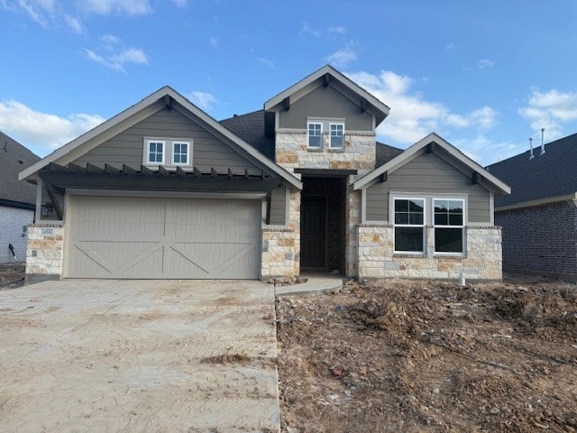 craftsman-style home featuring stone siding, an attached garage, and driveway