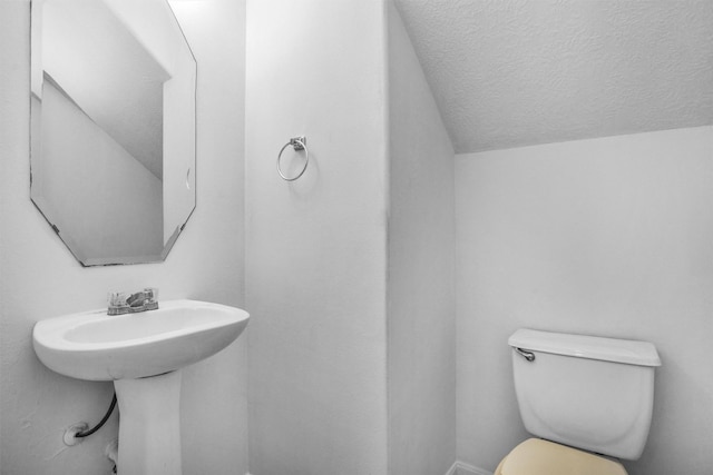 bathroom with toilet, a textured ceiling, and lofted ceiling