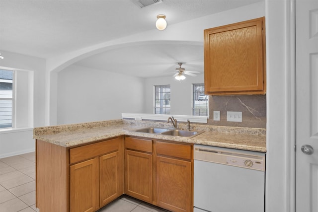 kitchen featuring light tile patterned floors, a peninsula, white dishwasher, and a sink