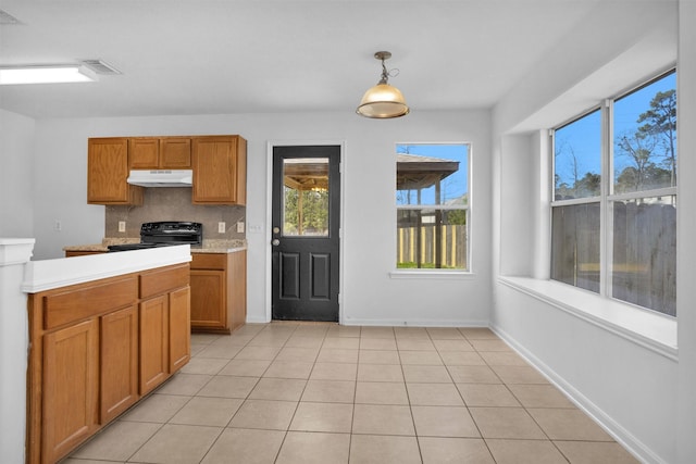 13757 Bighorn Trl, Willis, TX 77378 - kitchen with under cabinet range hood, black range with electric cooktop, light countertops, decorative backsplash, and brown cabinets