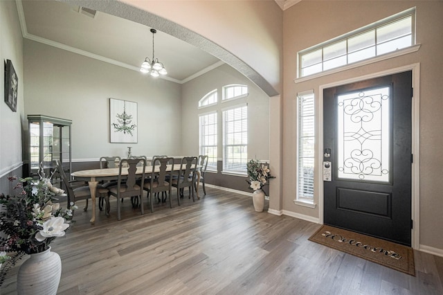 foyer with baseboards, visible vents, ornamental molding, wood finished floors, and a chandelier