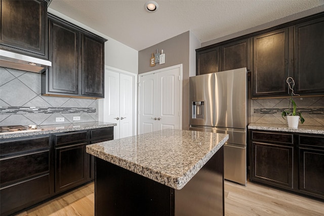 kitchen featuring stainless steel appliances, light wood-style floors, a kitchen island, and dark brown cabinets