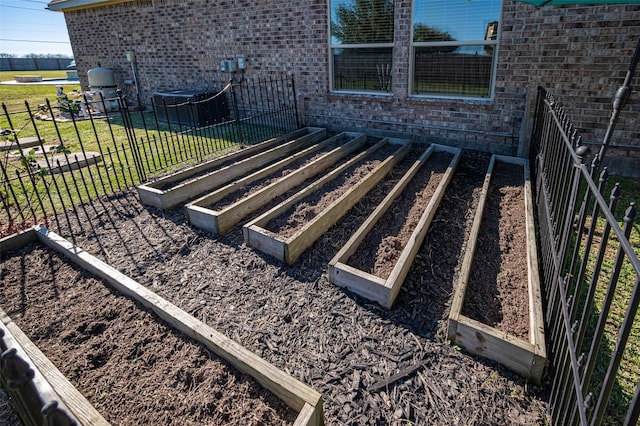 details featuring a garden, fence, central AC, and brick siding