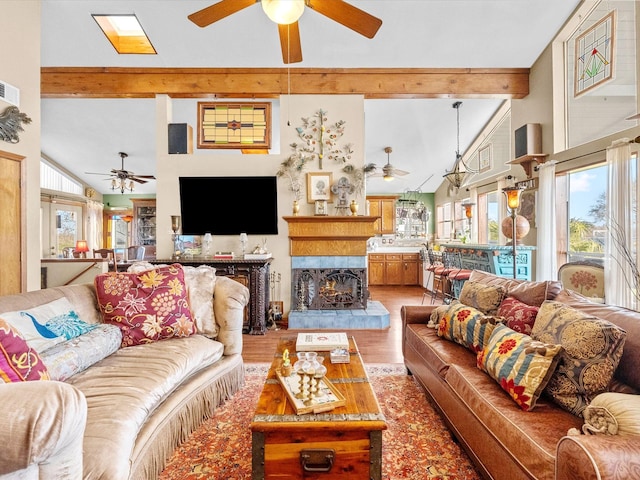 living area featuring light wood-style floors, a wealth of natural light, beam ceiling, and ceiling fan