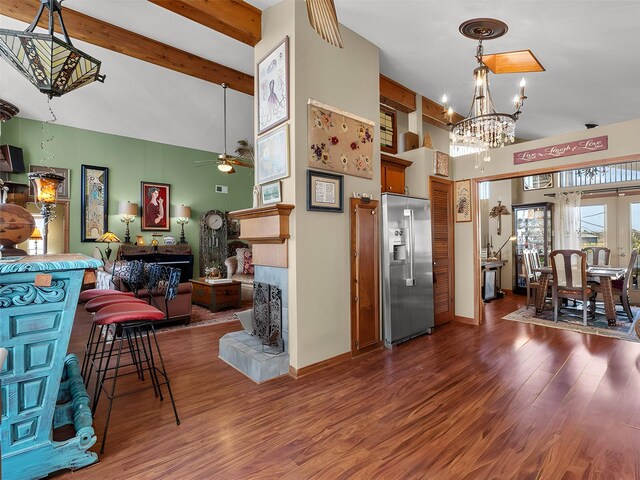 kitchen featuring high end refrigerator, a tiled fireplace, wood finished floors, beamed ceiling, and high vaulted ceiling