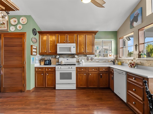 kitchen with white appliances, brown cabinets, and vaulted ceiling