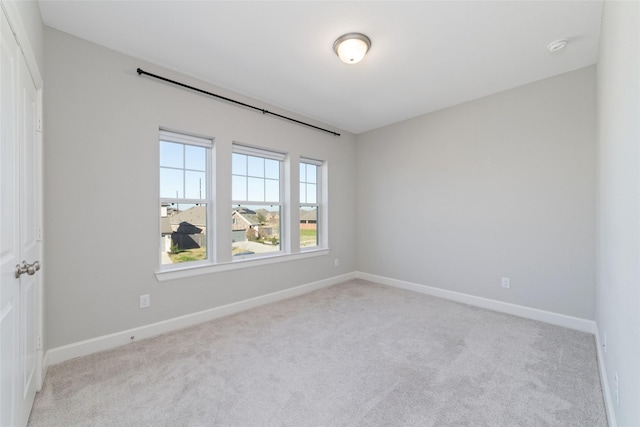 unfurnished room with light carpet and baseboards