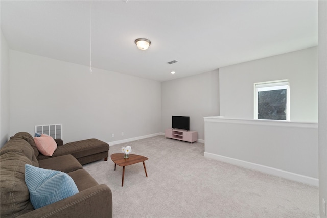 living area featuring baseboards, visible vents, and light colored carpet