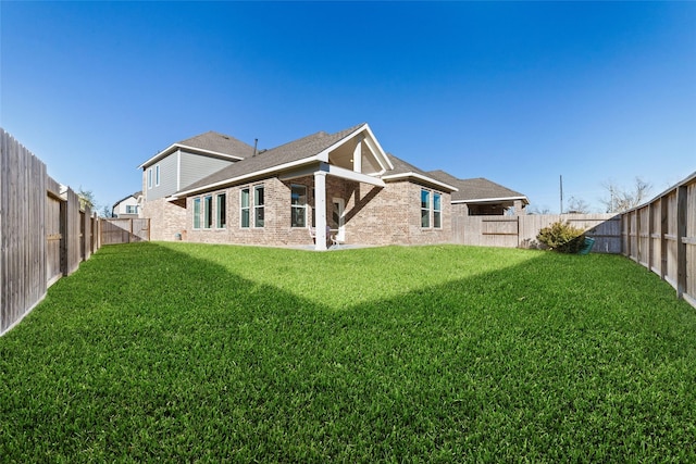 back of house featuring brick siding, a yard, and a fenced backyard