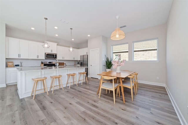 kitchen with white cabinetry, baseboards, light countertops, appliances with stainless steel finishes, and pendant lighting