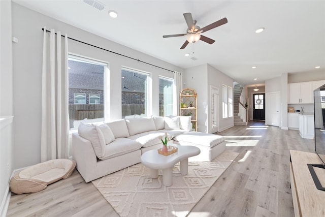 living area featuring recessed lighting, visible vents, light wood finished floors, and stairs