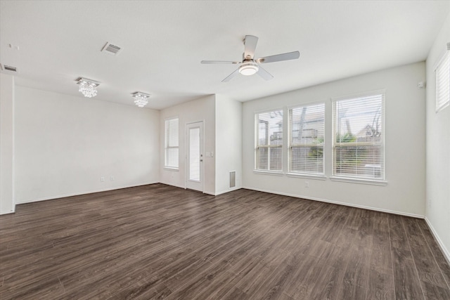 spare room featuring ceiling fan, dark wood finished floors, visible vents, and baseboards