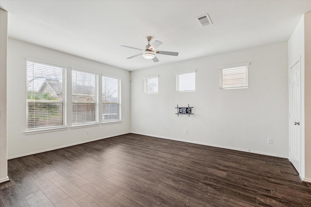 unfurnished room featuring visible vents, dark wood-style flooring, a ceiling fan, and baseboards