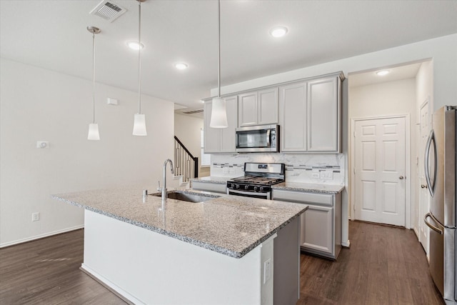 kitchen with stainless steel appliances, a sink, a kitchen island with sink, and pendant lighting