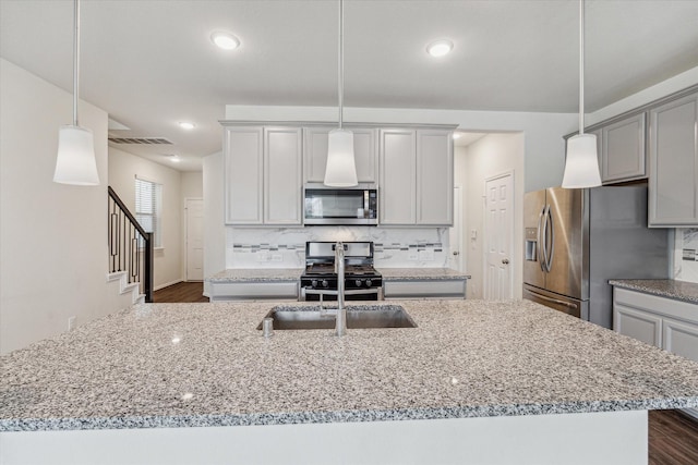 kitchen with visible vents, a kitchen island with sink, appliances with stainless steel finishes, and decorative light fixtures