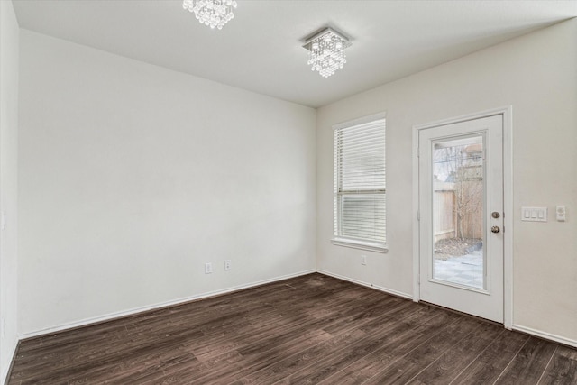 unfurnished room with dark wood-type flooring and a notable chandelier