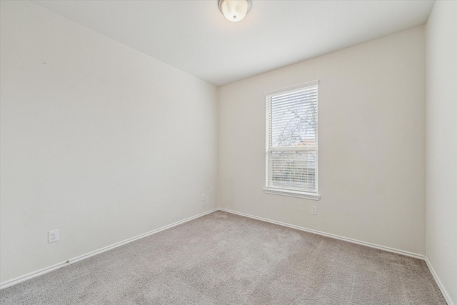 unfurnished room featuring light carpet and baseboards