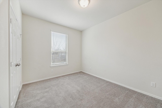 unfurnished room with light carpet and baseboards