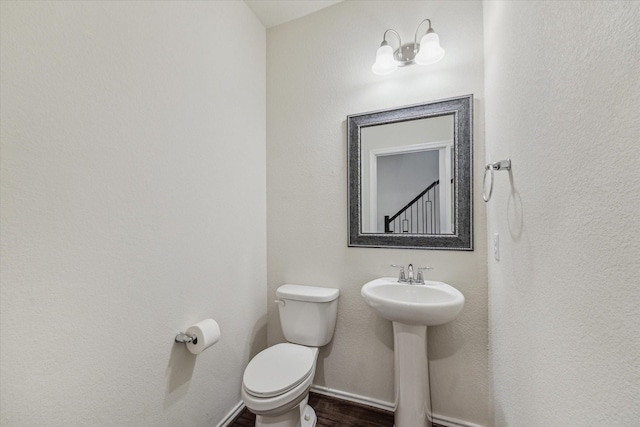 bathroom featuring a sink, wood finished floors, toilet, and baseboards