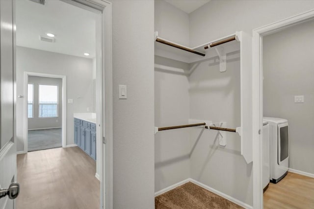 spacious closet featuring light wood-type flooring, washing machine and dryer, and visible vents