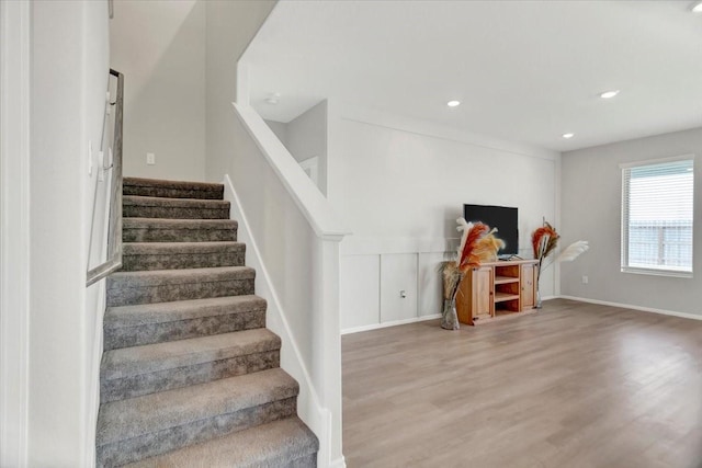 stairs with baseboards, wood finished floors, and recessed lighting