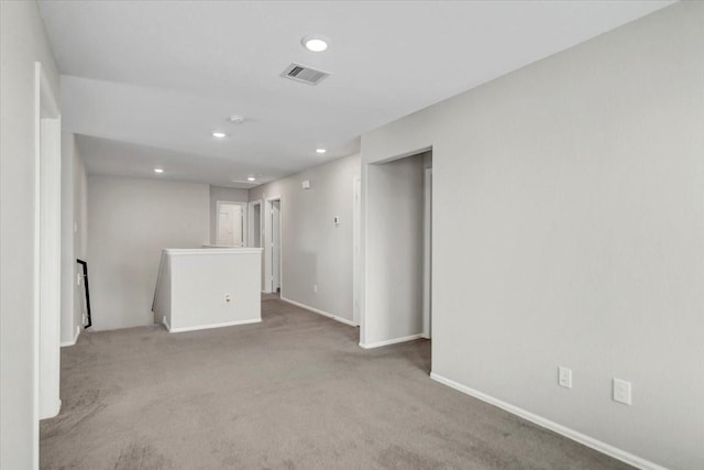 spare room featuring light colored carpet, visible vents, baseboards, and recessed lighting