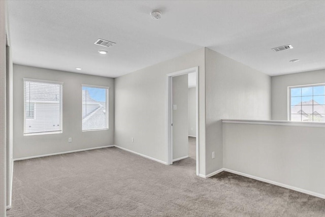 unfurnished room featuring light carpet, baseboards, and visible vents