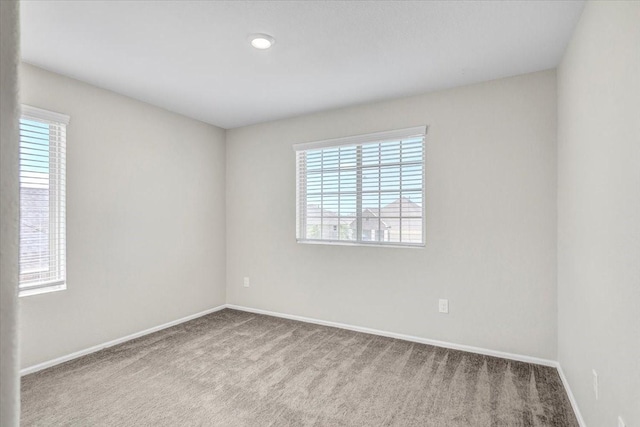 empty room featuring light carpet and baseboards